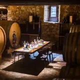 Cantine Valpolicella da visitare: un tavolo apparecchiato tra botti di legno e pietra, pronto per una degustazione.
