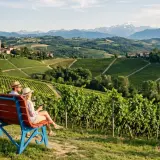 Coppia su una panchina ammira il panorama delle Langhe, un perfetto tour enogastronomico tra vigneti e borghi storici.