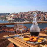 Un bicchiere di late bottled vintage porto, due calici e dolcetti su un tavolo con vista sulla città di Porto.