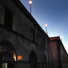 Edificio in mattoni con lampioni accesi al crepuscolo. L'insegna "Osteria del Principe" evoca il **frasca significato** di un luogo conviviale.