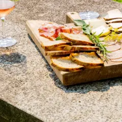 Tagliere di salumi, formaggi e pane, accompagnato da un bicchiere di vino rosato, per una perfetta degustazione vini Piemonte.