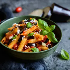 Piatto di pasta alla norma con melanzane, pomodoro e basilico, perfetto per un abbinamento vino.