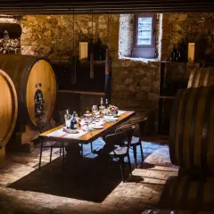 Cantine Valpolicella da visitare: un tavolo apparecchiato tra botti di legno e pietra, pronto per una degustazione.