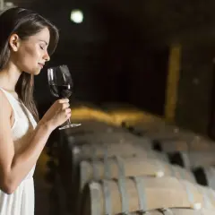 Donna in cantina assapora un bicchiere di vino rosso, un'esperienza che racchiude il vero degustazione significato.