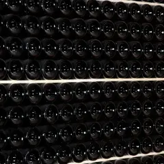 Fila di bottiglie scure, un'immagine che evoca il batonnage cos'è: la tecnica di mescolare il vino in botte per affinarlo.