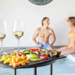 Coppia rilassata alle terme con degustazione di vino e frutta fresca. Un momento di puro piacere.