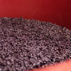 La feccia del vino, residuo della fermentazione, riposa in un contenitore rosso.