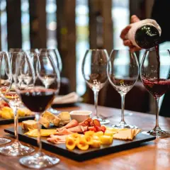 Calice di vino rosso versato, con taglieri di formaggi e salumi. Perfetti abbinamenti per un vino vespaiolo.