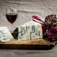 Gorgonzola e vino rosso su tagliere rustico, con radicchio e carciofo. Un perfetto gorgonzola abbinamento vino per un'esperienza gustativa.