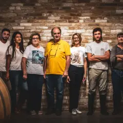 La famiglia al completo di Ca del Bric, in posa tra botti di legno e mattoni antichi, pronta a condividere la passione per il vino.