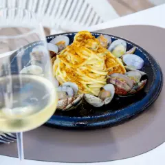 Un bicchiere di vino bianco, perfetto per gli abbinamenti con spaghetti alle vongole. Un piatto di mare invitante.