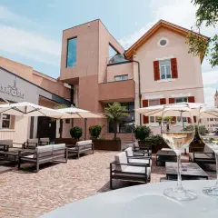 Terrazza accogliente con divani e ombrelloni, due calici di vino bianco in primo piano. La cantina St. Pauls sullo sfondo.
