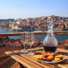 Un bicchiere di late bottled vintage porto, due calici e dolcetti su un tavolo con vista sulla città di Porto.