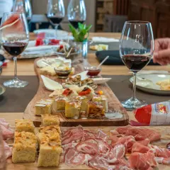 Un tavolo imbandito per una degustazione enogastronomica: salumi, formaggi, focacce e vino rosso invitano a un'esperienza di sapori.