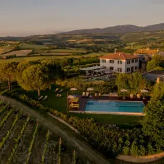 Un incantevole wine resort in Umbria, con vigneti rigogliosi, una piscina scintillante e colline ondulate al tramonto.