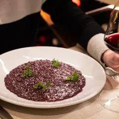 Risotto viola con prezzemolo, accompagnato da un calice di vino rosso. Perfetto per scoprire i migliori amarone abbinamenti.