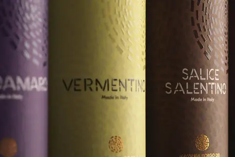 Etichetta vino esempio: bottiglie di Negroamaro, Vermentino, Salice Salentino e Primitivo, con dettagli dorati e texture uniche.
