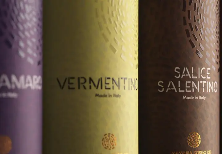 Etichetta vino esempio: bottiglie di Negroamaro, Vermentino, Salice Salentino e Primitivo, con dettagli dorati e texture uniche.