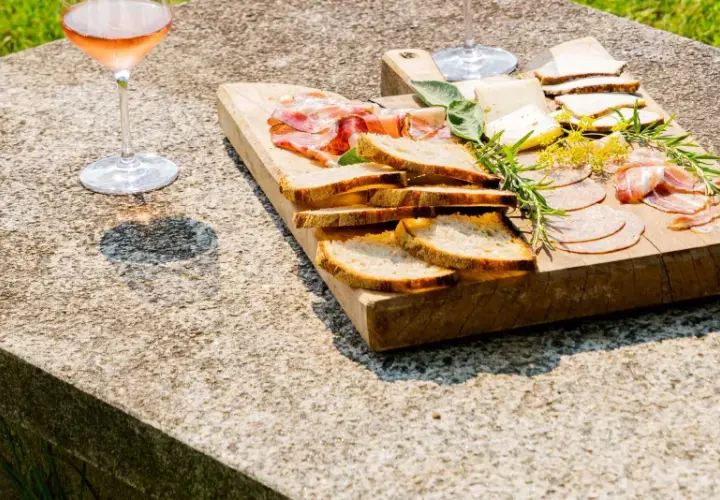 Tagliere di salumi, formaggi e pane, accompagnato da un bicchiere di vino rosato, per una perfetta degustazione vini Piemonte.