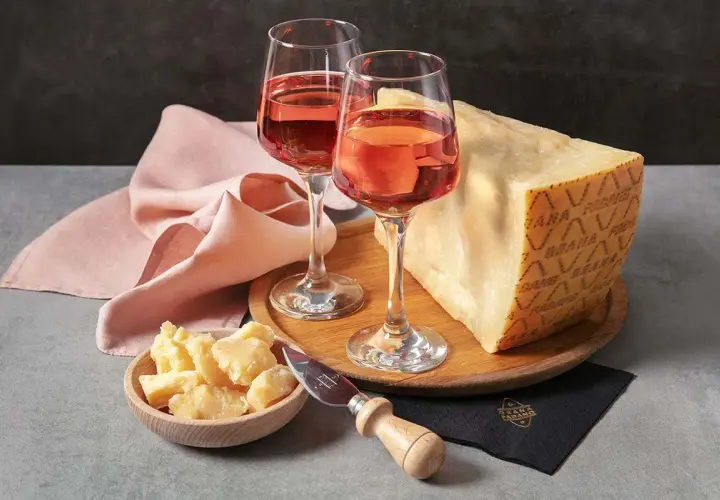Un bicchiere di vino rosato e un pezzo di Grana Padano, un abbinamento perfetto per un aperitivo.