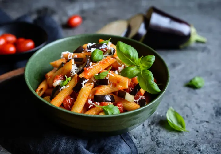 Piatto di pasta alla norma con melanzane, pomodoro e basilico, perfetto per un abbinamento vino.
