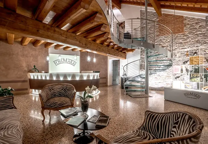 Interno di una cantina con reception, scala a chiocciola e esposizione di bottiglie. Ideale per cantine da visitare Valdobbiadene.
