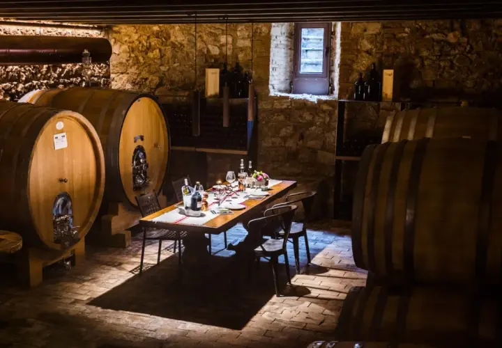 Cantine Valpolicella da visitare: un tavolo apparecchiato tra botti di legno e pietra, pronto per una degustazione.