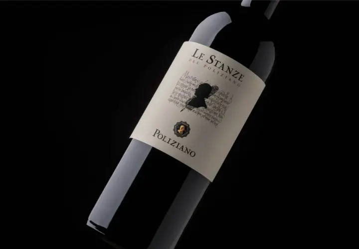 Bottiglia di vino rosso "Le Stanze del Poliziano" su sfondo nero. L'etichetta presenta un profilo silhouette e testo calligrafico.