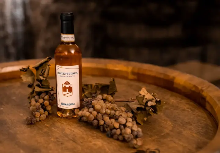 Bottiglia di Recioto di Soave con uva appassita e foglie secche, suggerendo i suoi abbinamenti.