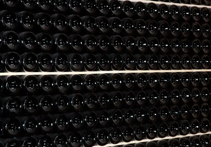 Fila di bottiglie scure, un'immagine che evoca il batonnage cos'è: la tecnica di mescolare il vino in botte per affinarlo.