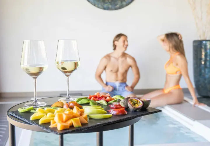 Coppia rilassata alle terme con degustazione di vino e frutta fresca. Un momento di puro piacere.