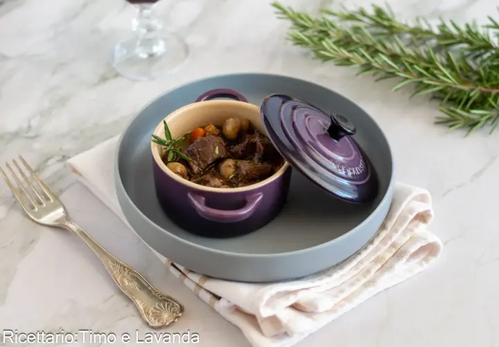 Un saporito stufato di manzo, perfetto per un vino per bourguignonne, servito in una cocotte viola con rosmarino.