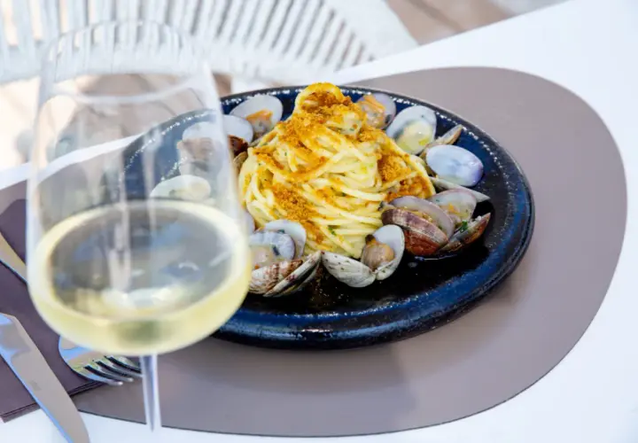 Un bicchiere di vino bianco, perfetto per gli abbinamenti con spaghetti alle vongole. Un piatto di mare invitante.