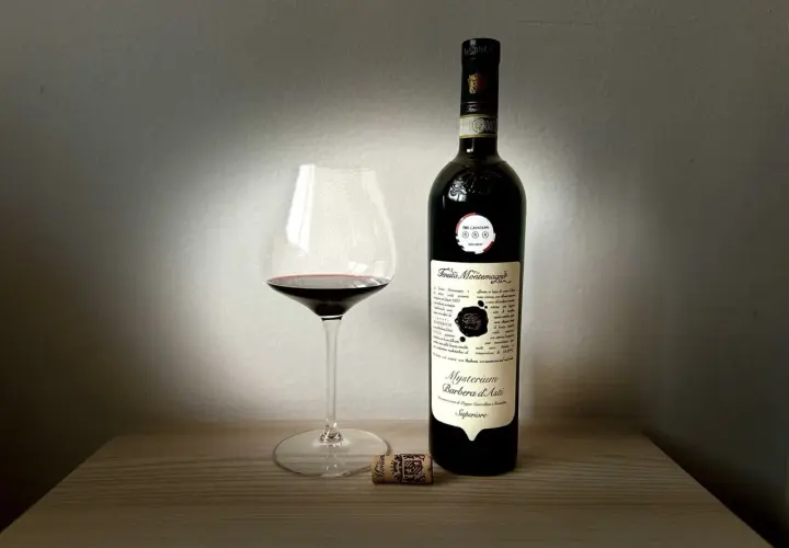 Un calice di Barbera d'Asti Mysterium e la sua bottiglia, un assaggio delle migliori cantine Asti.