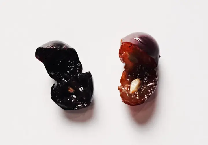 Due acini d'uva tagliati a metà, uno scuro e uno più chiaro, evocano la macerazione carbonica del vino.
