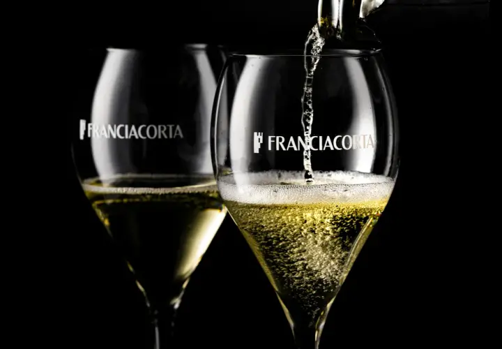 Due calici di Franciacorta Saten, uno viene riempito, perfetti per ogni abbinamento.
