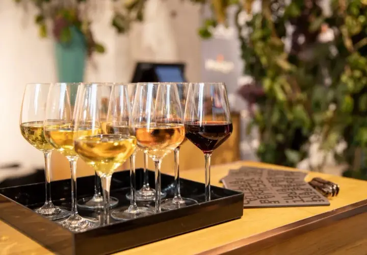 Calici di vino bianco, rosato e rosso su un vassoio nero. Un'esperienza di degustazione che non è barricata, ma aperta a tutti i sapori.