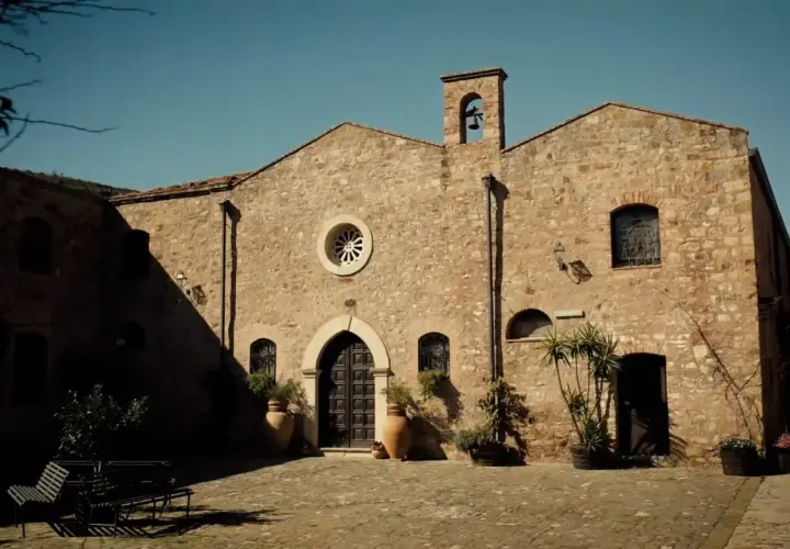 L'abbazia Santa Anastasia, con la sua facciata in pietra e il campanile, si affaccia su un cortile acciottolato.