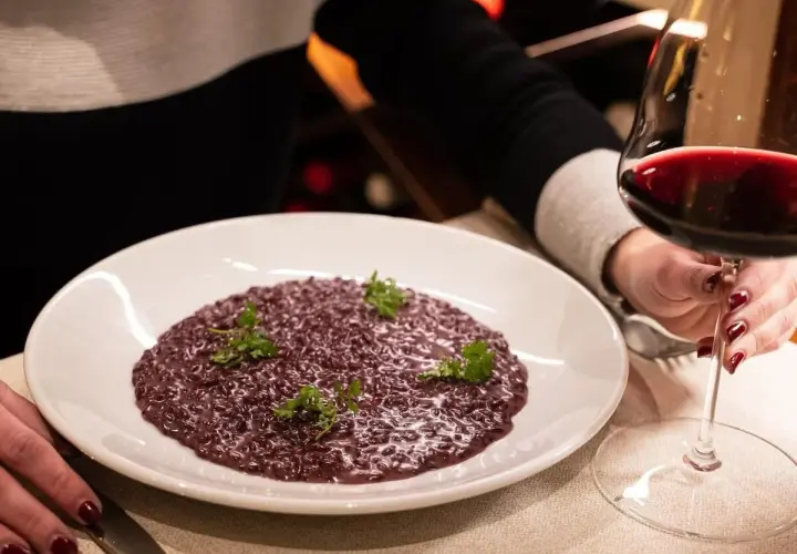 Risotto viola con prezzemolo, accompagnato da un calice di vino rosso. Perfetto per scoprire i migliori amarone abbinamenti.