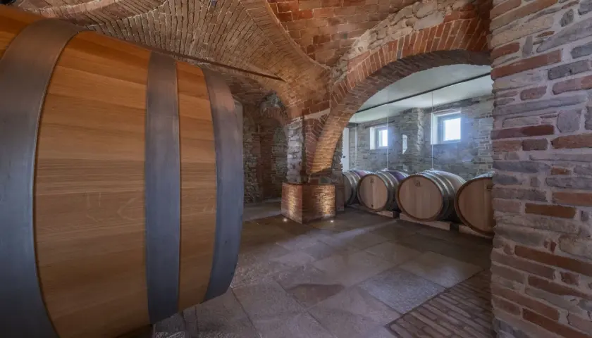 Cantina della tenuta Bussia con botti di legno e soffitto a volta in mattoni.