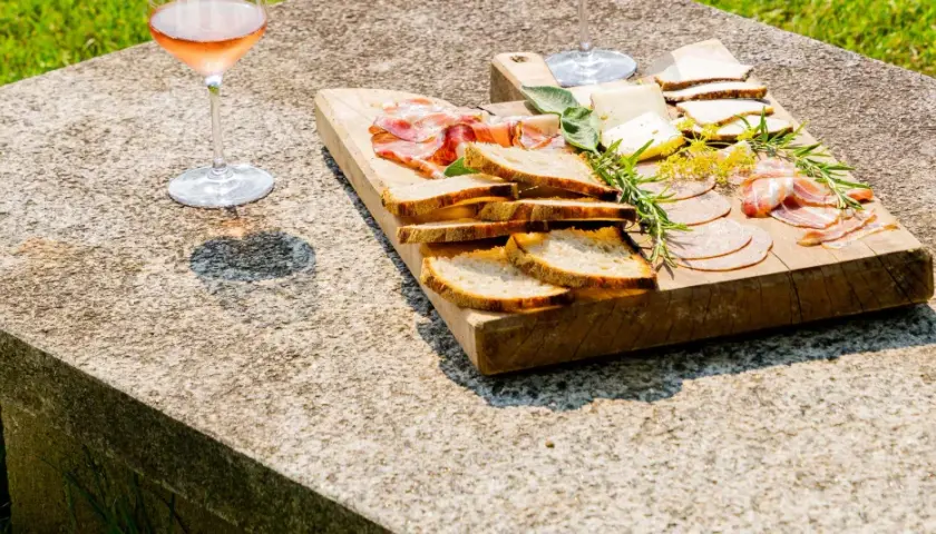 Tagliere di salumi, formaggi e pane, accompagnato da un bicchiere di vino rosato, per una perfetta degustazione vini Piemonte.