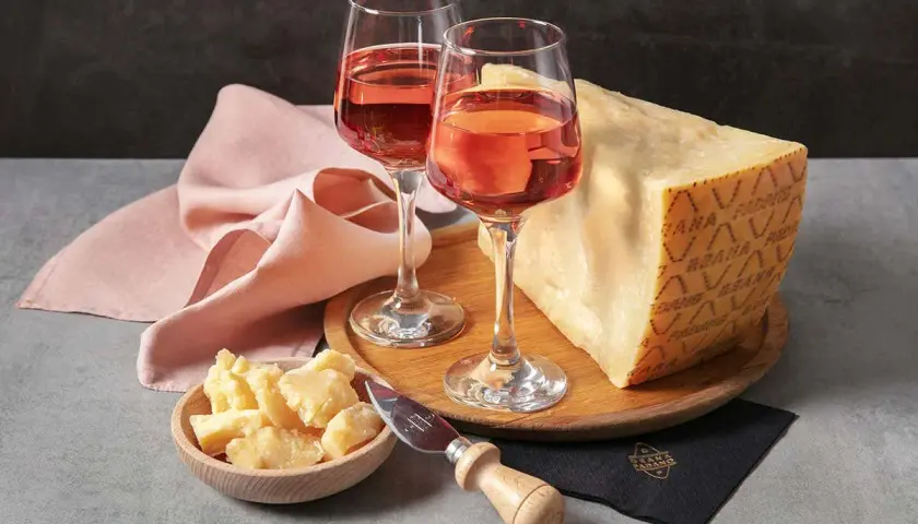 Un bicchiere di vino rosato e un pezzo di Grana Padano, un abbinamento perfetto per un aperitivo.