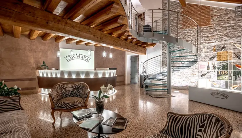 Interno di una cantina con reception, scala a chiocciola e esposizione di bottiglie. Ideale per cantine da visitare Valdobbiadene.