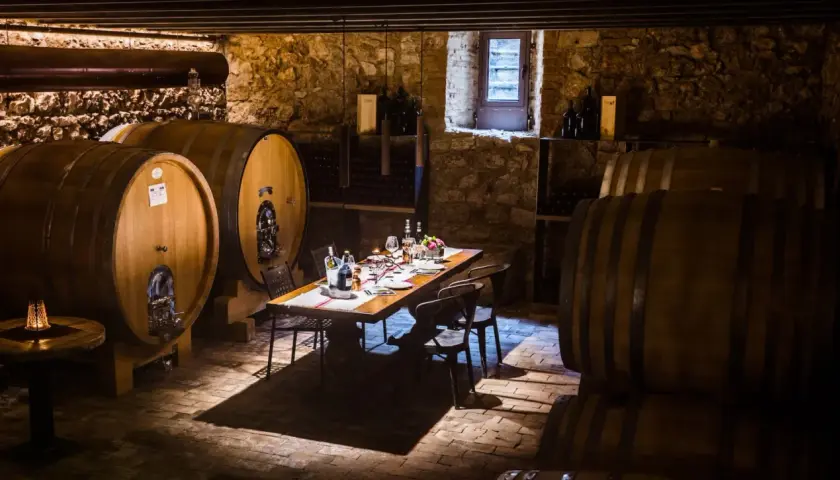 Cantine Valpolicella da visitare: un tavolo apparecchiato tra botti di legno e pietra, pronto per una degustazione.
