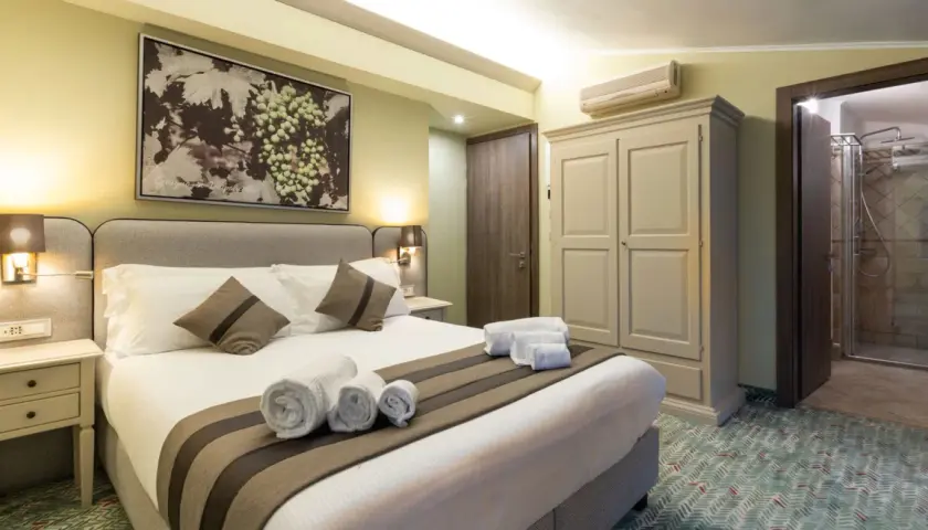 Camera accogliente con letto comodo, quadro di uva e un invito a dormire in cantina a Valpolicella.