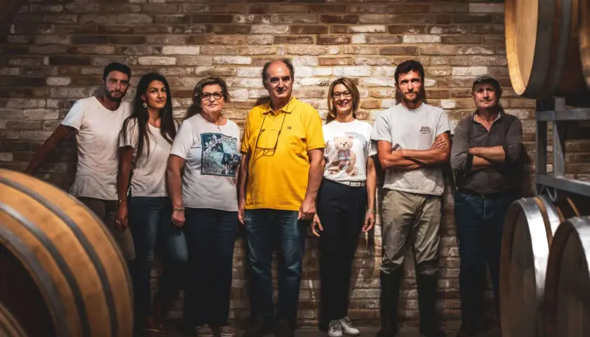 La famiglia al completo di Ca del Bric, in posa tra botti di legno e mattoni antichi, pronta a condividere la passione per il vino.