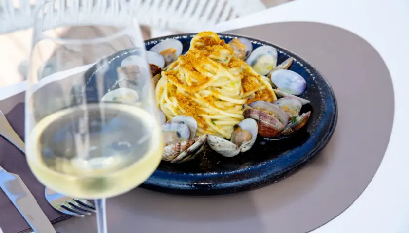 Un bicchiere di vino bianco, perfetto per gli abbinamenti con spaghetti alle vongole. Un piatto di mare invitante.