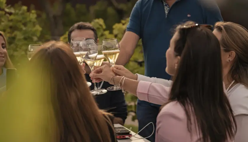Un brindisi al festival della Franciacorta, con amici che alzano i calici di bollicine dorate in un'atmosfera di festa.