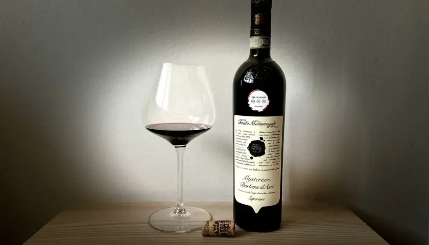 Un calice di Barbera d'Asti Mysterium e la sua bottiglia, un assaggio delle migliori cantine Asti.