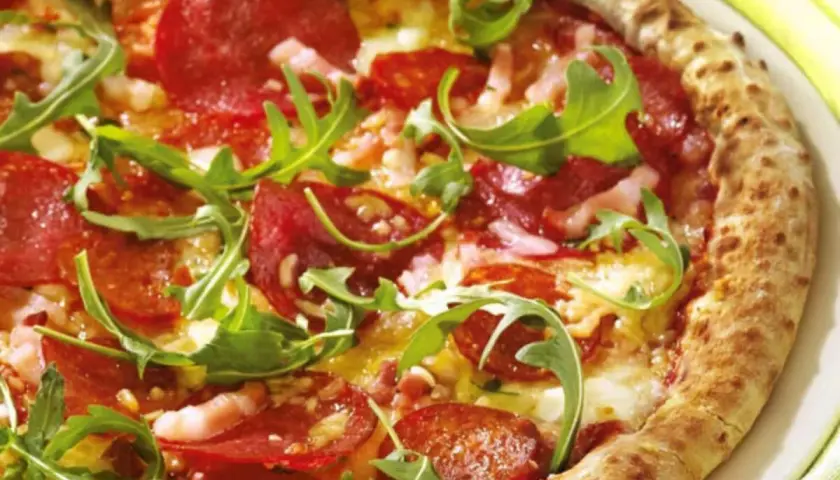 Pizza con salame piccante, rucola e formaggio filante. Un abbinamento classico e gustoso per un'esperienza culinaria indimenticabile.